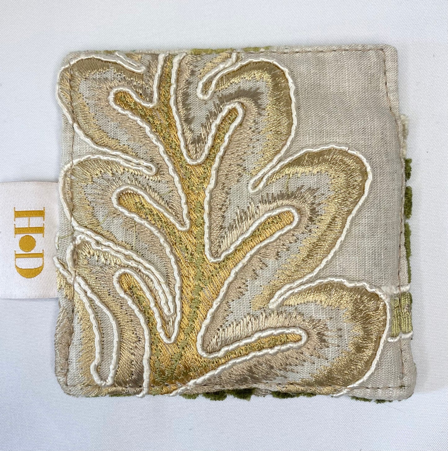 Textured fabric square with gold leaf pattern on a white background