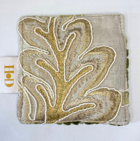 Textured fabric square with gold leaf pattern on a white background